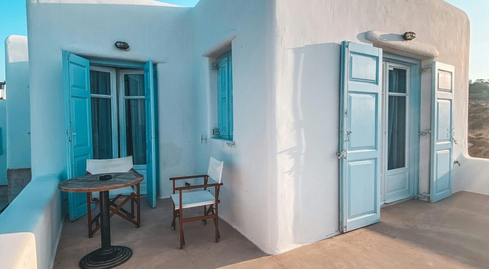 Quaint Greek house with classic blue shutters and terrace in idyllic setting.